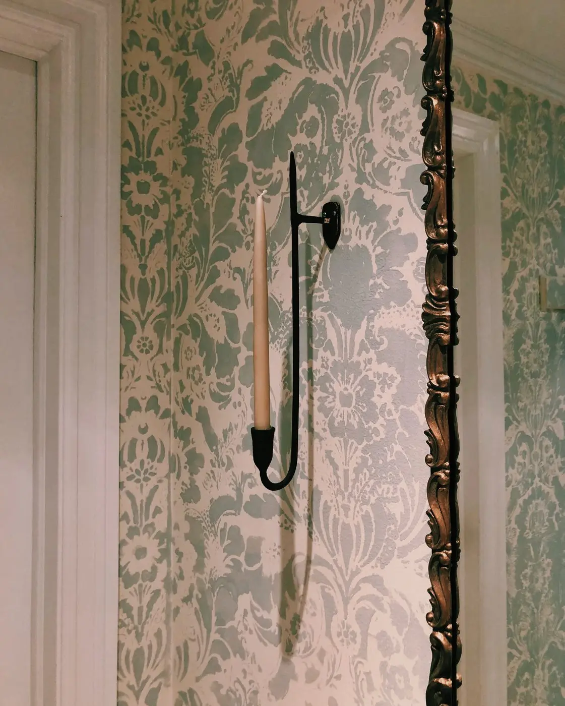 Candle sconce against damask stenciled wall